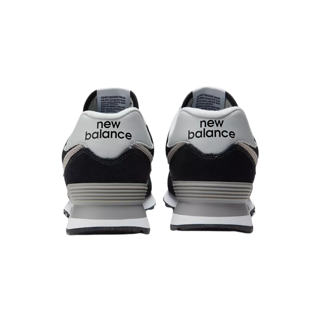 Back view of Men’s New Balance 574 casual sneaker in black/white/grey – featuring stitched heel counter, layered textures, and contrasting heel tab.