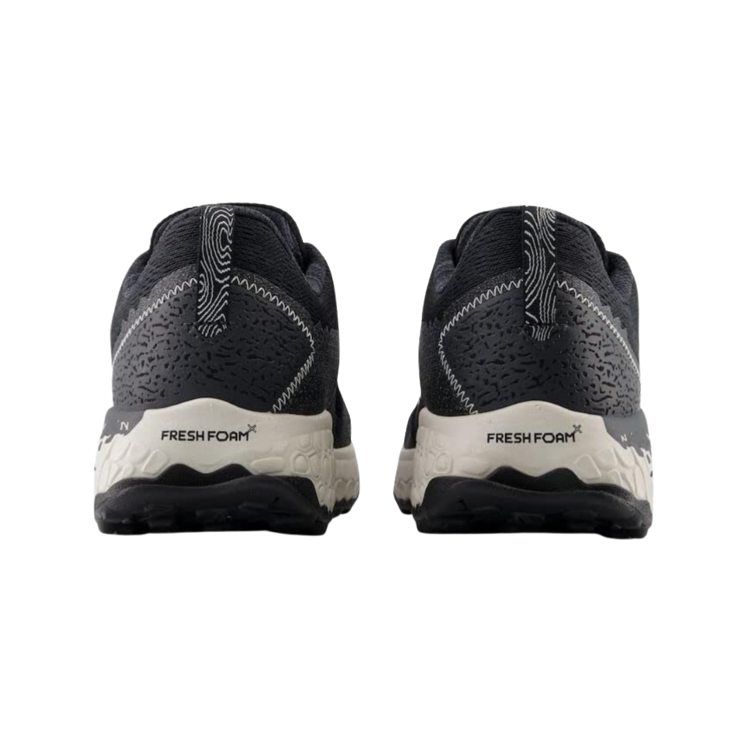 Back View of Men’s New Balance Fresh Foam X Hierro v7 trail running shoe in black reflection with white – featuring structured heel counter, pull tab for easy on and off, and reflective accents for enhanced visibility.