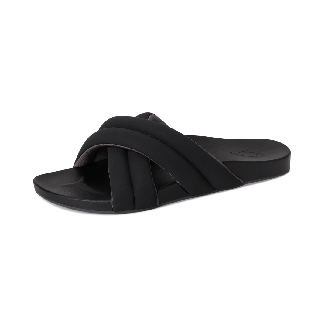 Angled view of Women’s Olukai Hila sandal in black – features include a water-friendly synthetic strap, plush cushioned footbed with arch support, slim and stylish profile, and a textured outsole for added stability.