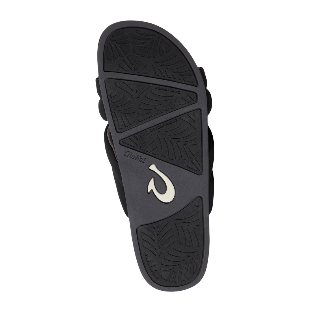 Bottom view of Women’s Olukai Hila sandal in black – features include a non-marking rubber outsole, wave-inspired tread pattern for enhanced traction, and a flexible sole ideal for both indoor and outdoor wear.