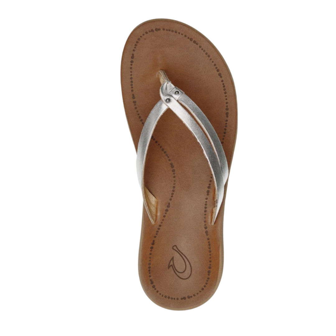 Top view of Women’s Olukai Kapehe Luana sandal in Silver/Sahara – features include a smooth leather strap in a metallic silver tone, soft toe post, suede-textured footbed with arch support, and a rounded shape for natural foot alignment.