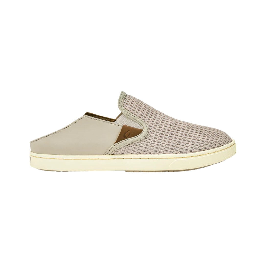 Side View of Women’s Olukai Pehuea slip-on sneaker in tapa – featuring a breathable mesh upper, dual elastic side panels, and a removable cushioned footbed for all-day comfort.