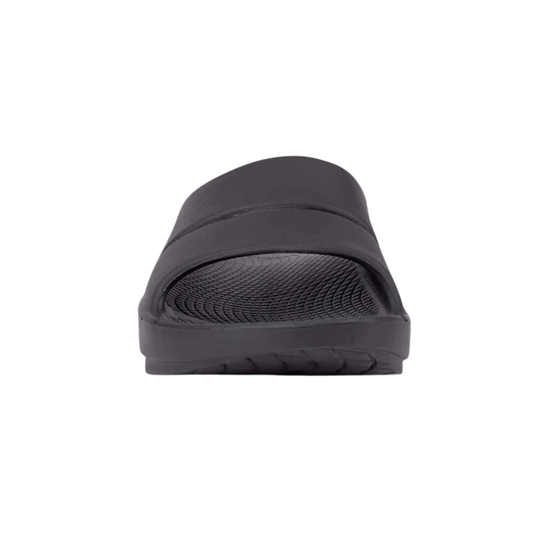 Front view of Unisex OOFOS Ooahh Slide Sandal in black – featuring a wide, seamless synthetic strap, anatomically molded footbed, subtle textured surface for grip, and a clean, minimal look in solid black.